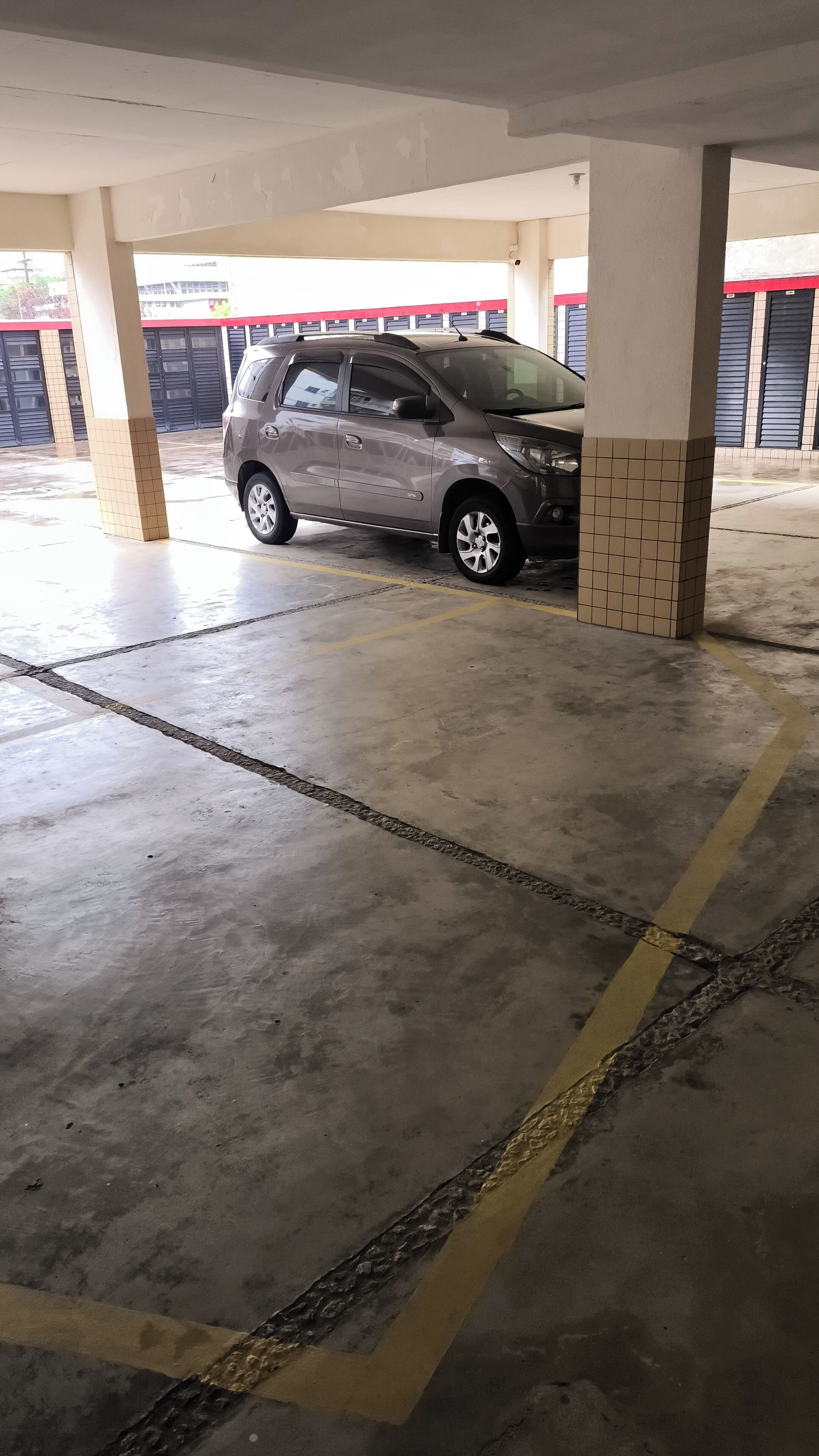 Un garaje para estacionar con un coche aparcado bajo un pilar.
