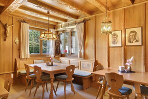 Une salle à manger en bois avec une grande table, des bancs et des chaises.