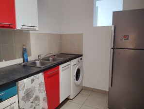 Eine Küche mit Waschmaschine, Kühlschrank und Spüle.