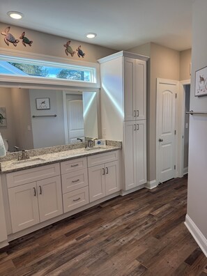 A kitchen with white cabinetry, a granite countertop, and wooden flooring. - Relaxing 3-bedroom house close to
Holden Beach! (Supply)