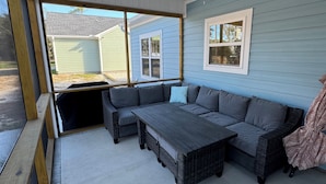 A covered patio with a sectional sofa, a table, and a ceiling fan. - Relaxing 3-bedroom house close to
Holden Beach! (Supply)