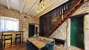 A rustic interior with a wooden dining table, blue chairs, a staircase, and stone walls. - Holiday Home Tranquilla with heated pool (Blato)