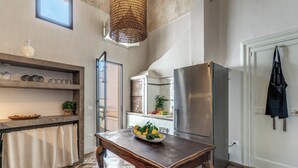 Una cucina con un tavolo di legno, un frigorifero, una finestra e una borsa appesa.