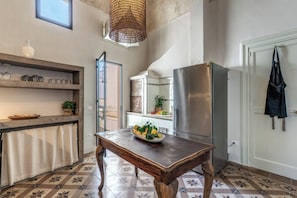 Una cucina con un tavolo di legno, un frigorifero, una finestra e una borsa appesa.
