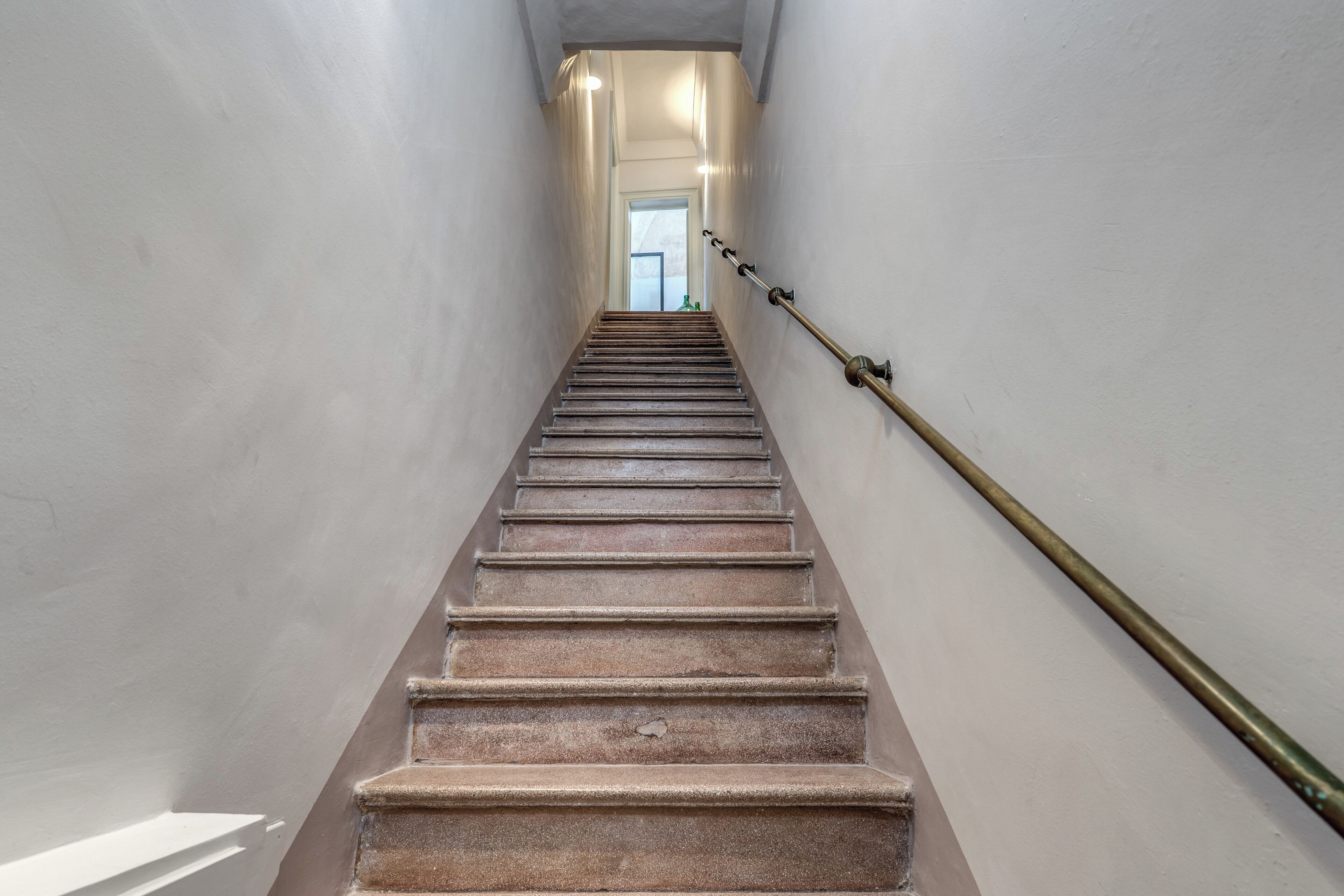 A staircase with a handrail, leading to a door at the top.