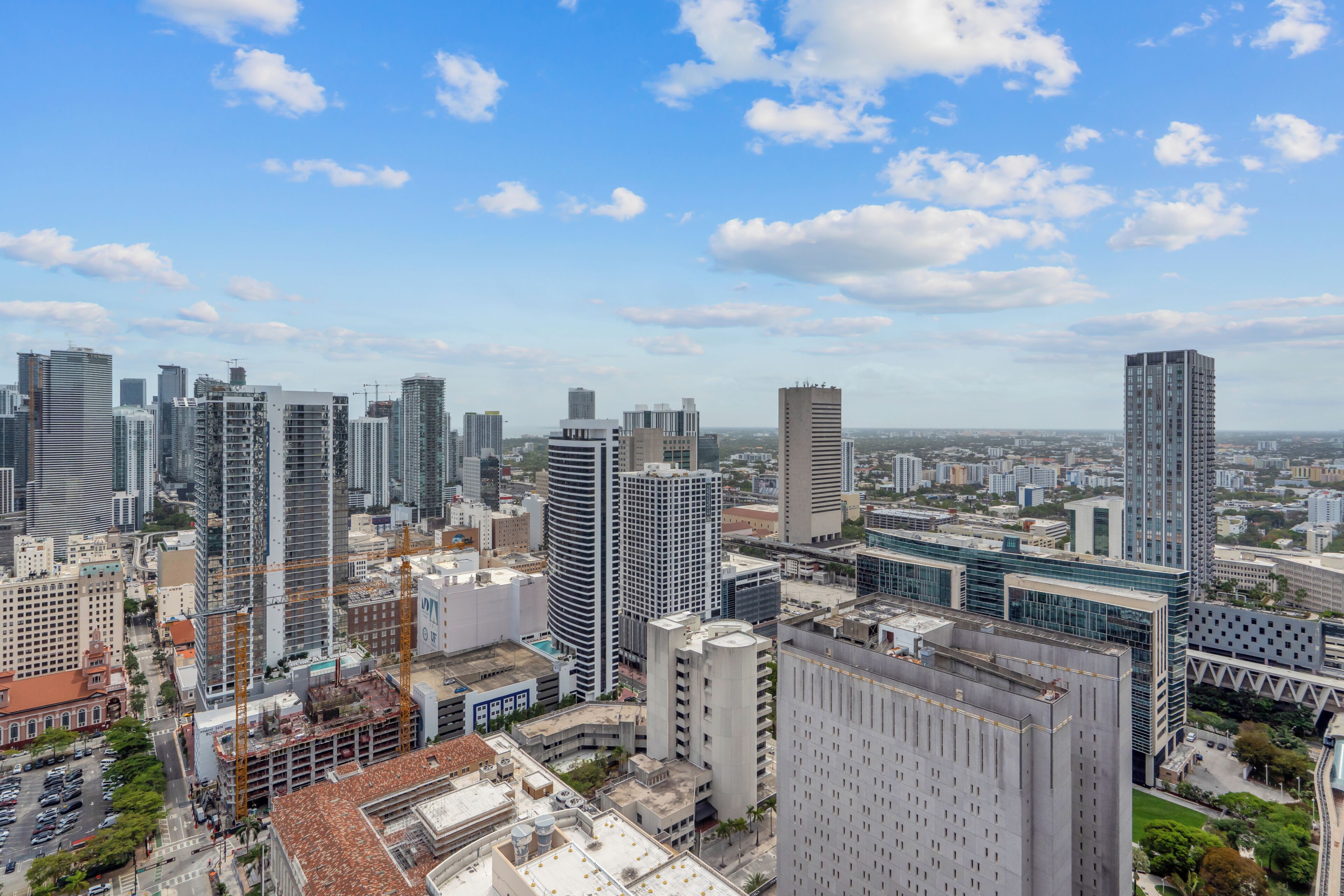 Une vue urbaine avec des immeubles modernes de grande hauteur, un chantier de construction et un ciel bleu dégagé.
