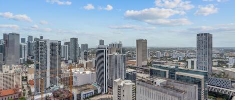 Une vue urbaine avec des immeubles modernes de grande hauteur, un chantier de construction et un ciel bleu dégagé.