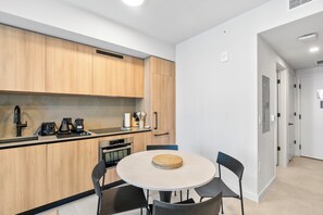 A modern kitchen with wooden cabinets, a round table with chairs, and a coffee machine. - 501 Building - Condo Miami - We Host (Miami)