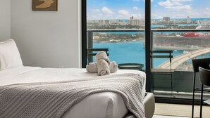 Una camera d'albergo con un letto, vista sulla città e un balcone con una sedia.