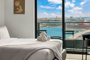 A hotel room with a bed, a view of the cityscape, and a balcony with a chair. - 501 Building - Condo Miami - We Host (Miami)