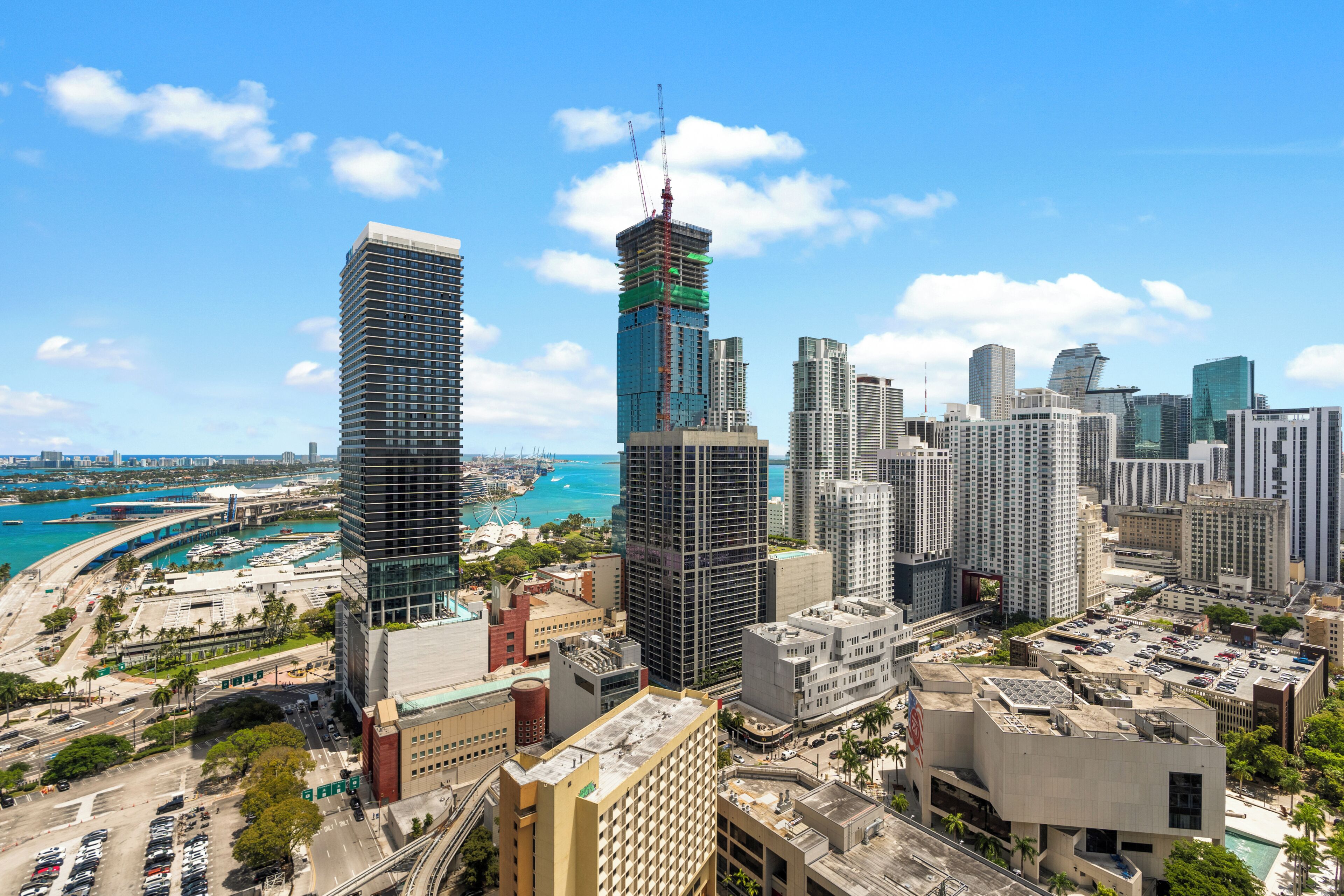 Un paysage urbain avec de hauts immeubles, un port de plaisance et un ciel dégagé.