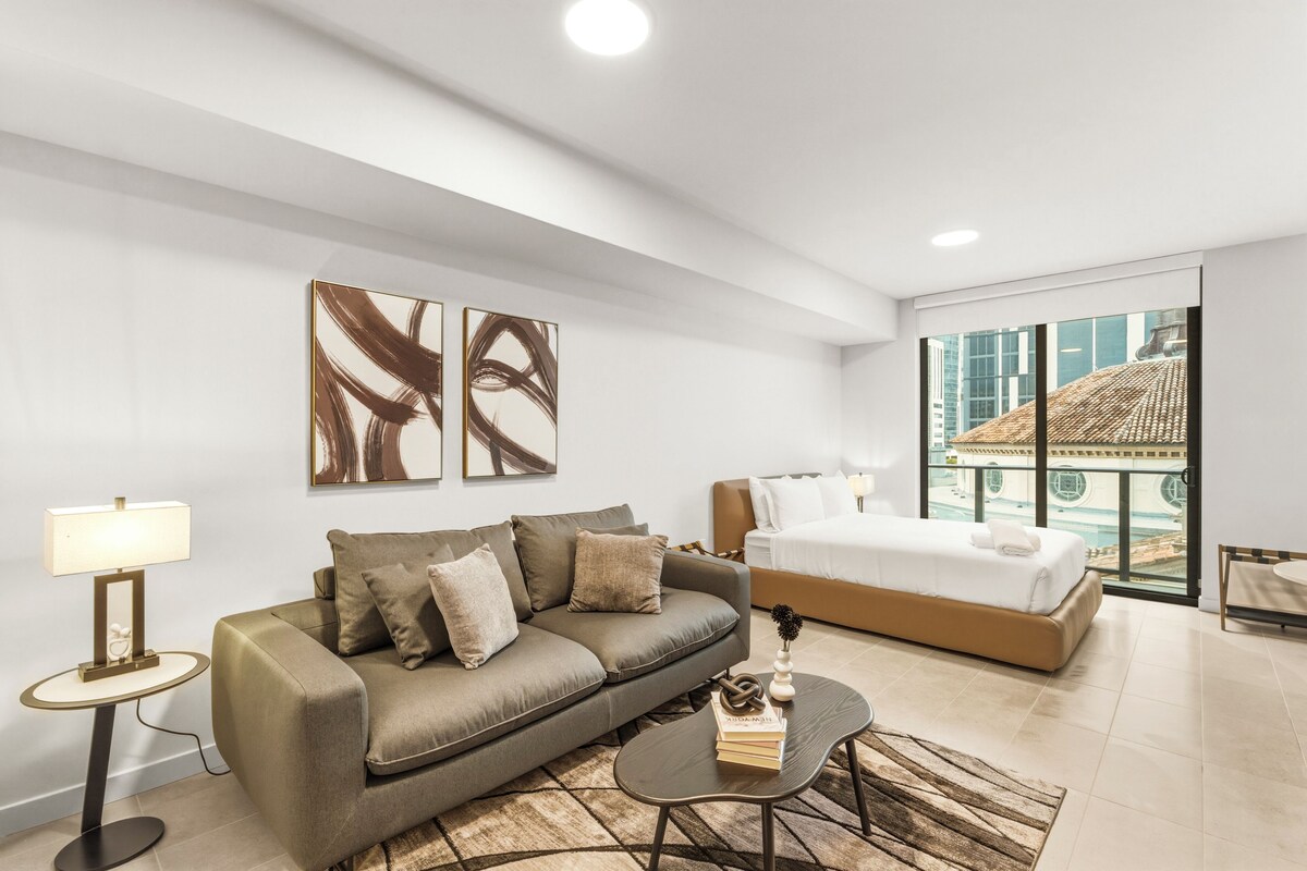 A modern hotel room with a sofa, a bed, a coffee table, and artwork on the walls.