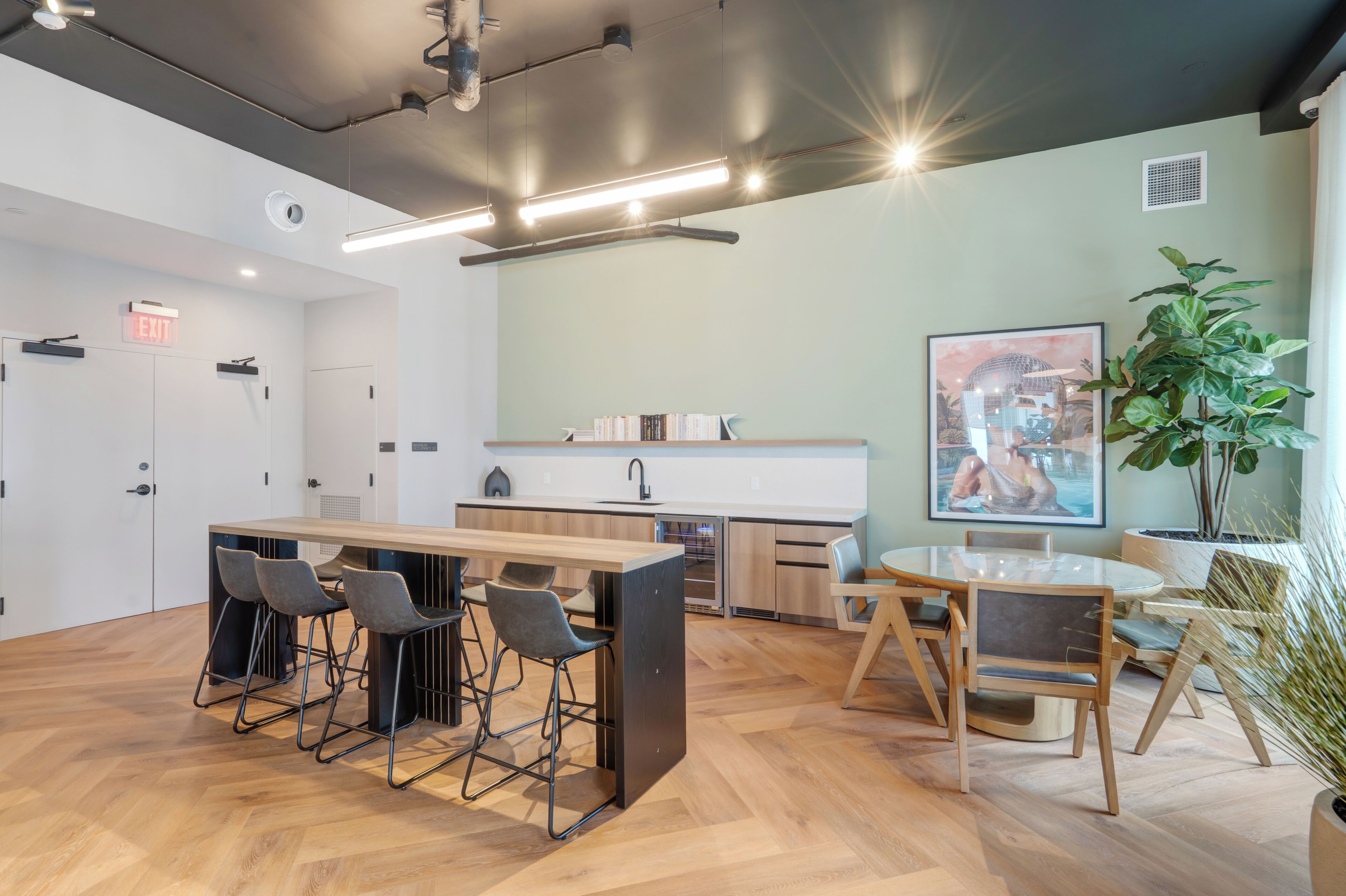 A modern kitchen with bar stools, a dining table, and chairs.