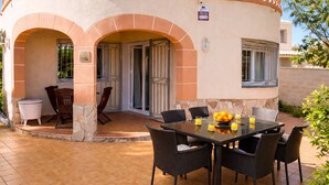 Ein Patio mit einem Esstisch, umgeben von Korbstühlen.