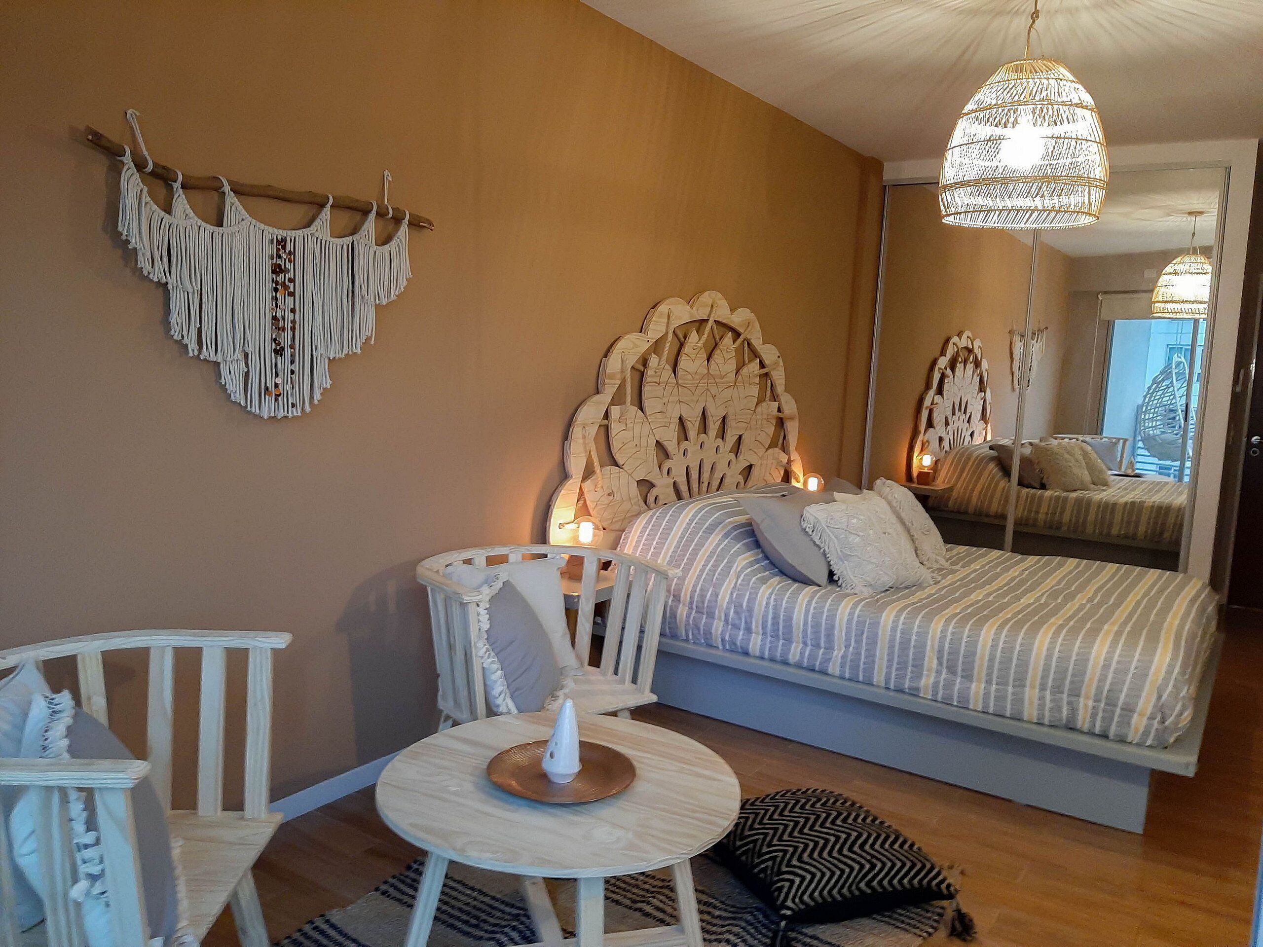 Un dormitorio con cama, mesita de noche, silla y espejo.