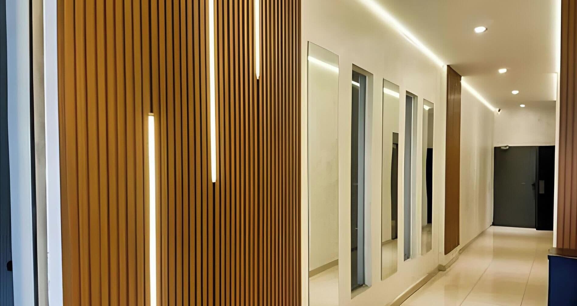 Um corredor moderno com ripas verticais de madeira, iluminação embutida e painéis espelhados.