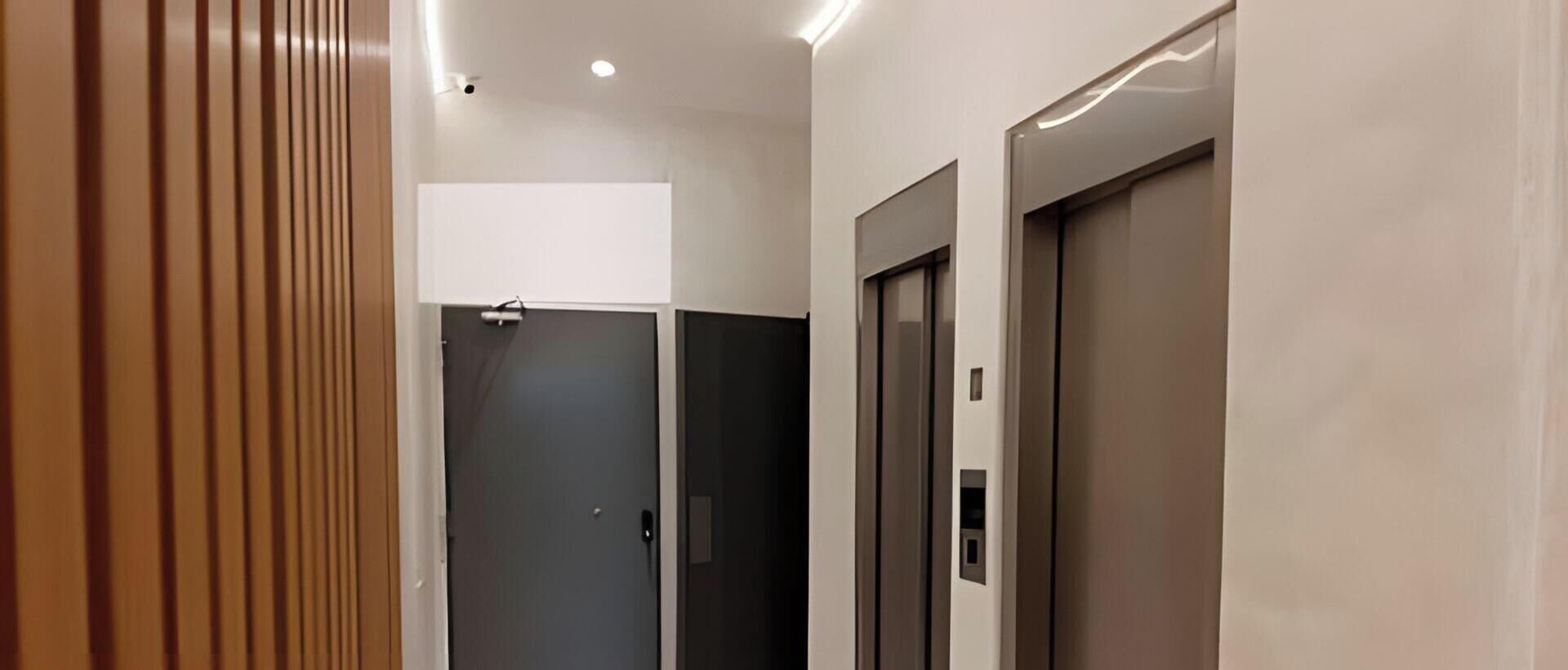 Un ascensor moderno con acabados metálicos, una puerta con manija y un panel de control.
