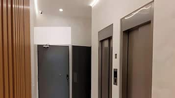 Un ascensor moderno con acabados metálicos, una puerta con manija y un panel de control.