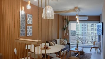 Een moderne woonkamer met een bank, eettafel, stoelen en een balkon met uitzicht over de stad.