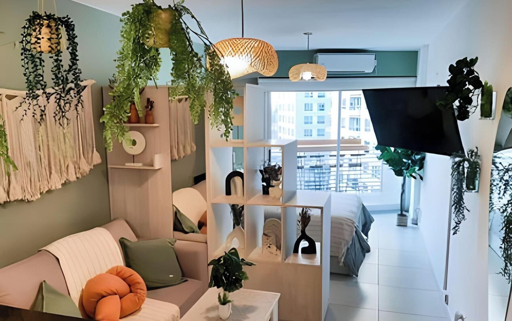 Een moderne woonkamer met een bank, een salontafel en een televisie. Er staan planken met decoratieve objecten en planten.