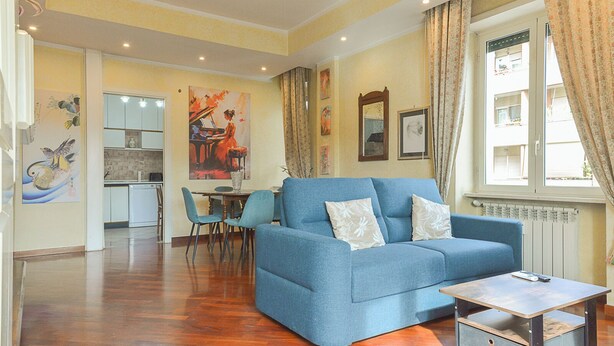 Un salon avec un canapé bleu, une table basse et un coin repas comprenant des chaises et une table.