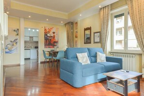 Ein Wohnzimmer mit einem blauen Sofa, einem Couchtisch und einem Essbereich mit Stühlen und einem Tisch.