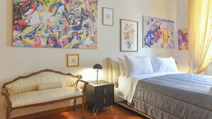 Une chambre à coucher avec un lit, une chaise, une table de chevet et trois tableaux accrochés au mur.