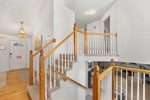 Una escalera con balaustres de madera y un rellano alfombrado.