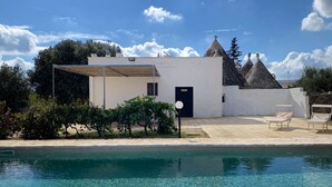 Ein modernes Gebäude mit Pool, überdachter Terrasse und einem kleinen Garten.