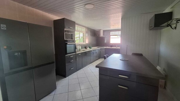 Una cocina moderna con armarios oscuros, microondas integrado y una isla grande con cajones.