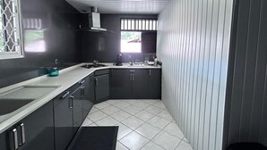 Una cocina compacta con armarios oscuros, una encimera blanca y suelo de baldosas.