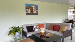 Una sala de estar con un sofá, dos sillones, una mesita de centro y una planta en maceta.