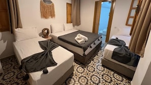 A hotel room with two beds, a patterned floor, and a view through an open door. - RIAD HOUCINE (Marrakech)