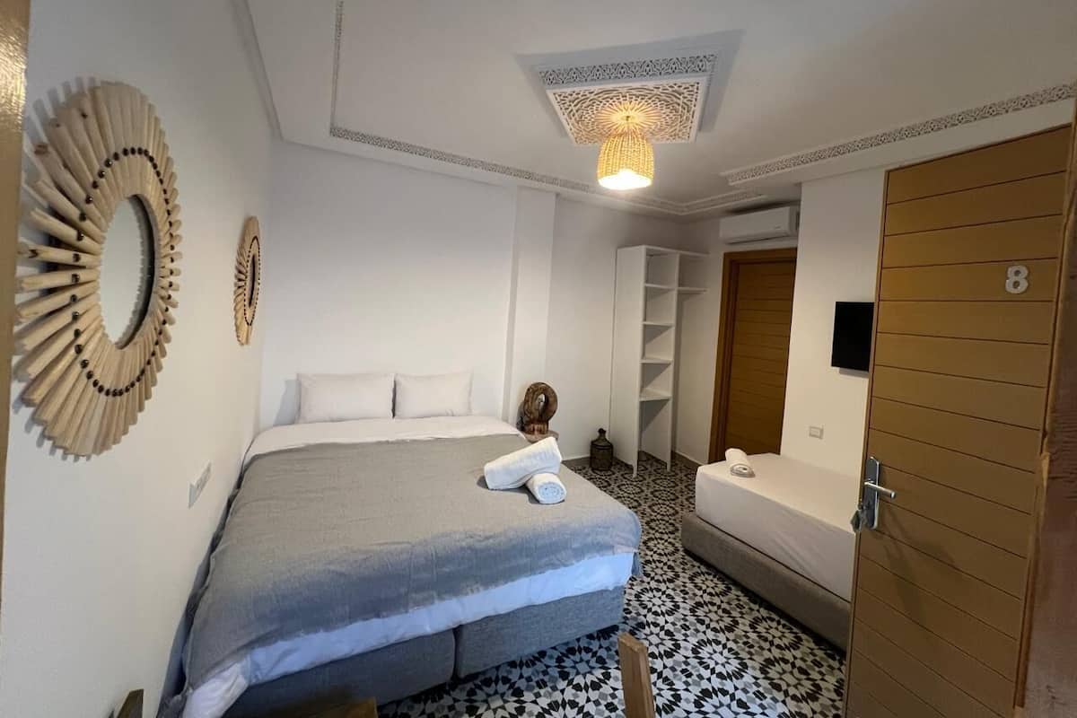 A hotel room with a bed, a bedside table, a chair, a wardrobe, and a bathroom.