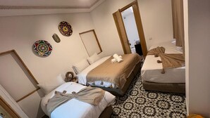 A hotel room with two beds, a patterned floor, and decorative wall art. - RIAD HOUCINE (Marrakech)