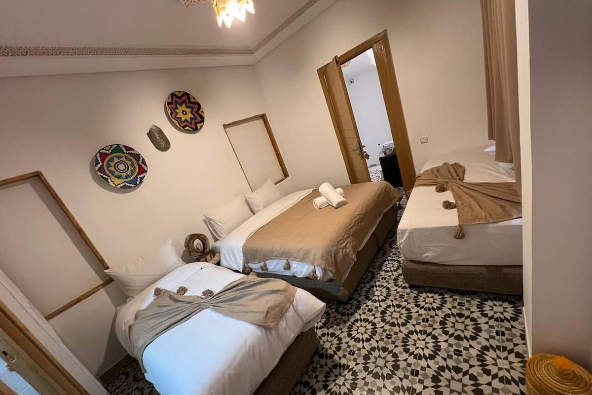A hotel room with two beds, a patterned floor, and decorative wall art.