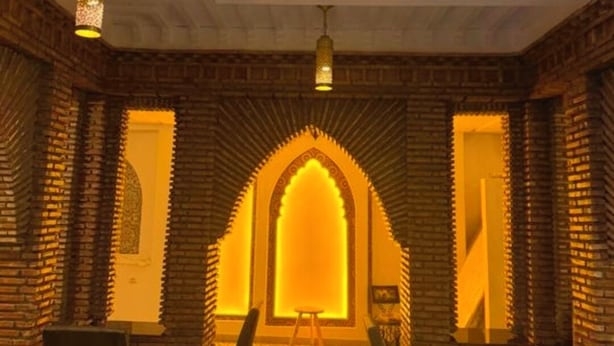 A restaurant with a high ceiling, brick walls, and a central archway. - RIAD HOUCINE (Marrakech)
