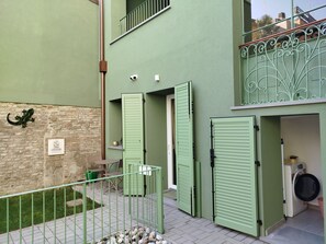 A building with green shutters, a brick wall, and a metal gate.
