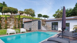 A swimming pool with lounge chairs, a stone wall, and a small building with a staircase. - Holiday Home 'Casa Da Oliveira' with Shared Pool, Wi-Fi and Air Conditioning (Dornelas)