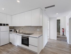 A modern kitchen with white cabinetry, a built-in oven, a microwave, and a sink. - Holiday Home 'Casa Da Oliveira' with Shared Pool, Wi-Fi and Air Conditioning (Dornelas)