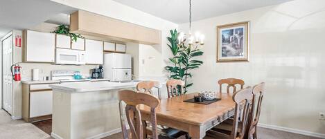 A modern kitchen with white appliances, a wooden dining table, and chairs.