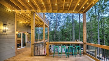 A wooden deck with a table and chairs, a gate, and a view of trees.