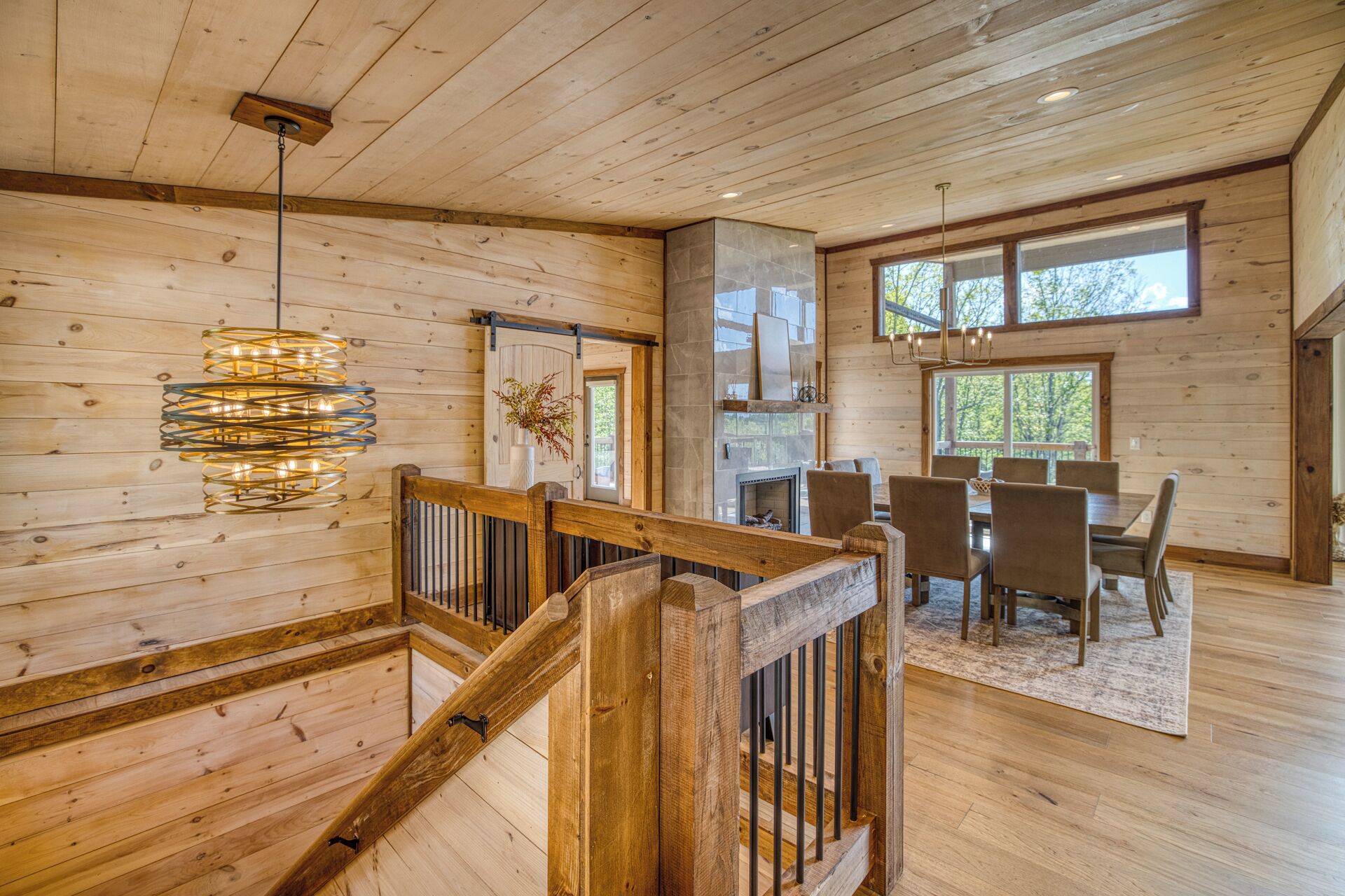 A wooden interior with a staircase, dining area, and large windows.