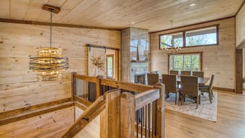 A wooden interior with a staircase, dining area, and large windows.