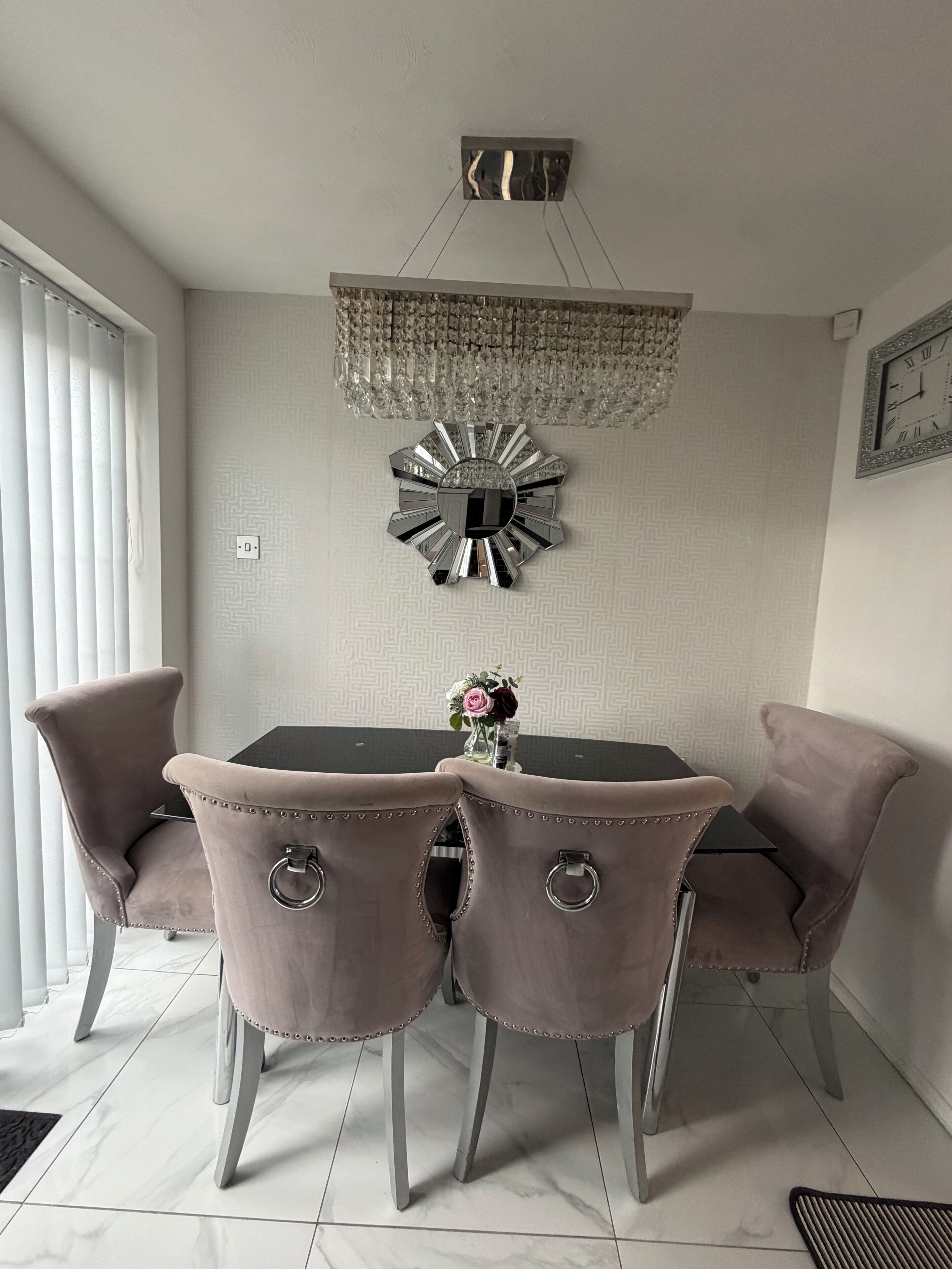 A dining area with a chandelier, a decorative mirror, and a clock on the wall.