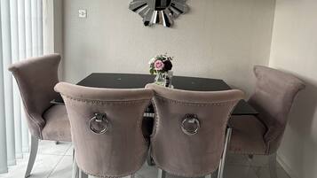 A dining area with a chandelier, a decorative mirror, and a clock on the wall.