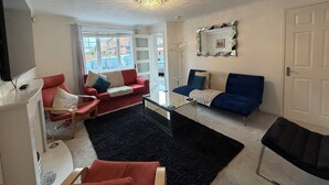 Un salon avec deux canapés, une table basse, un téléviseur et un lustre.