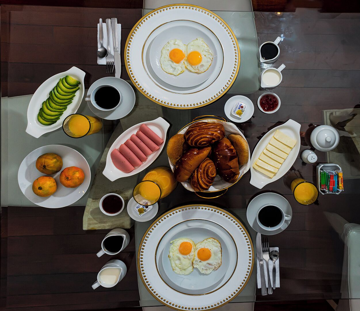 A breakfast table with plates of eggs, pastries, and fruit.