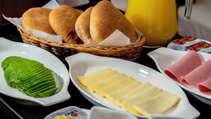 Un ricco buffet per la colazione con pane, formaggio, prosciutto e verdure verdi.