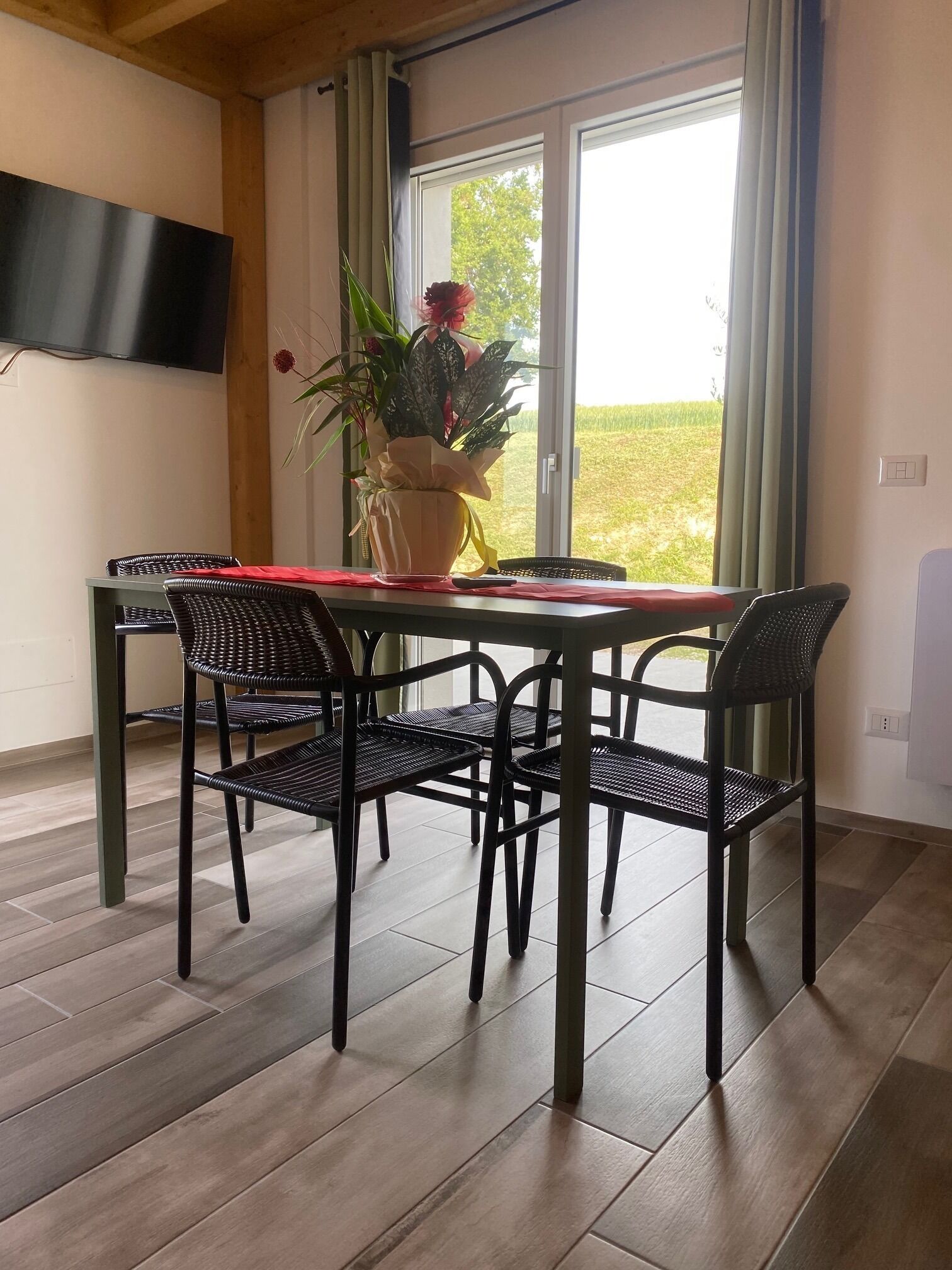 Een eethoek met een tafel, vier stoelen, een potplant en een raam met gordijnen.